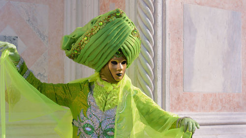 Person wearing mask and green costume during carnival