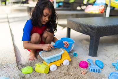 Cute girl playing with toys at beach