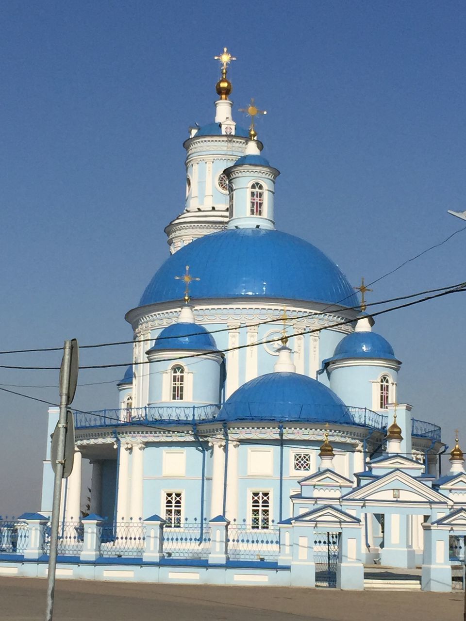 building exterior, architecture, built structure, clear sky, low angle view, blue, religion, church, travel, day, spirituality, place of worship, travel destinations, sky, outdoors, transportation, hanging, sunlight