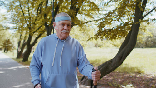 Senior man walking with nordic walking poles in park