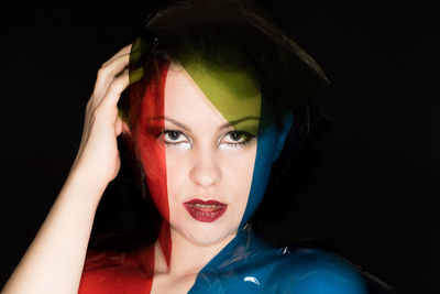 Portrait of fashion model with colorful plastic against black background