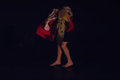 Woman with fabrics against black background