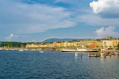 Boats moored in harbor against sky in city