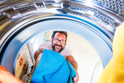 Portrait of man putting clothes in washing machine