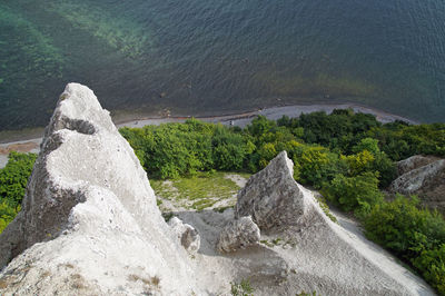 High angle view of rocks by sea against mountain