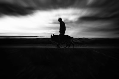 Silhouette man on beach against sky during sunset