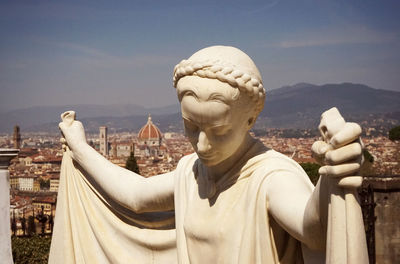 Sculpture on a grave near the convent san miniato al monte, view over the city of florence.