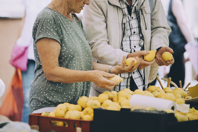 Midsection of senior couple shopping for lemons at street market in city