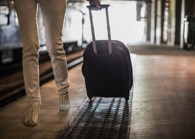 Low section of businesswoman with suitcase walking on railway station platform