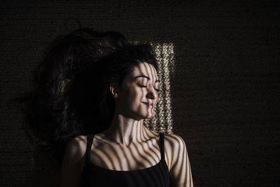 Smiling woman with blinds shadow sleeping on jute at home