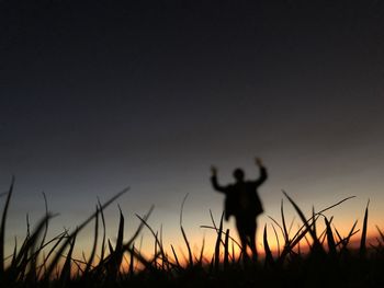 Silhouette man standing on field against sky during sunset