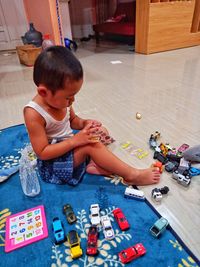 A little boy is playing number puzzle and toy car in the house at night