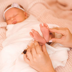 Mother holding legs of sleeping baby at home