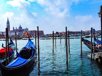 Gondolas moored in canal against sky