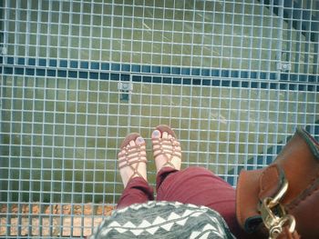 Low section of woman standing on metallic footbridge over danube river