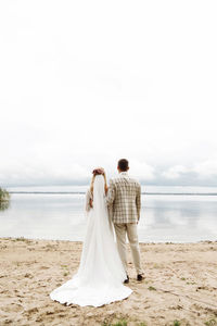 Rear view of couple holding hands against sky