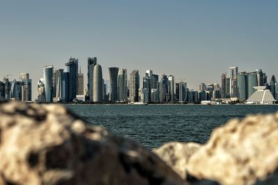 Sea by modern buildings against clear sky