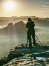 Rear view of man photographing against sky