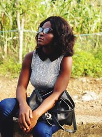 Young woman wearing sunglasses sitting outdoors