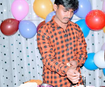 Rear view of man holding balloons against wall