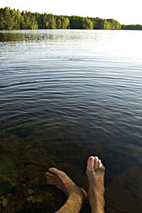 Low section of man relaxing on lake