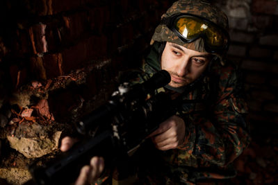 Young soldiers with guns, a soldier in equipment and with arms inspects a ruined house outside the