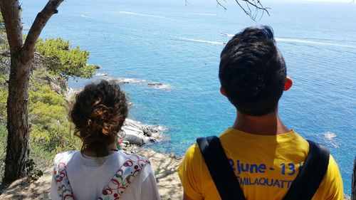 Rear view of friends standing by sea against sky