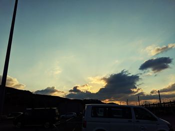 Cars on road against sky at sunset