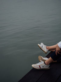 Low section of person holding ice cream over lake