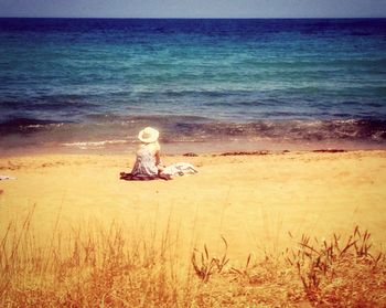 Rear view of people sitting on beach