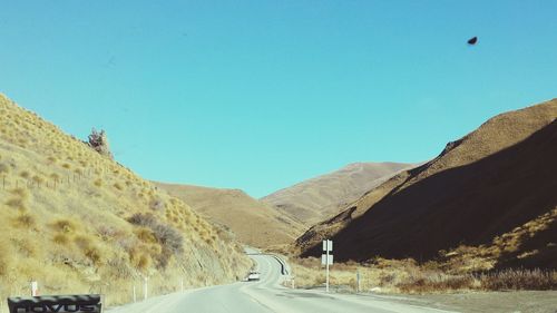 Road by mountains against clear blue sky