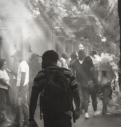 Rear view of backpacker walking on crowded footpath in city