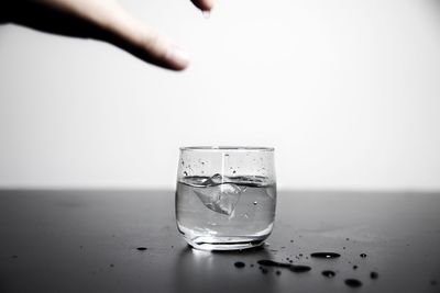 Close-up of hand on glass against white background