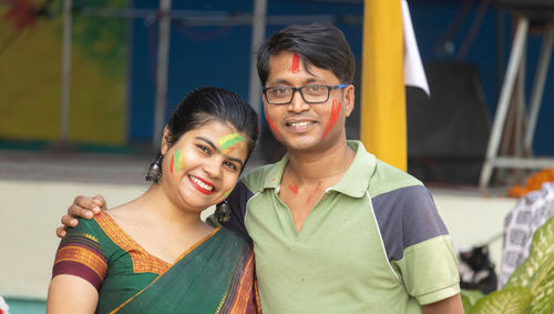 An indian couple with colorful faces looking at camera in holi - the festival of colors