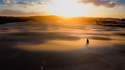 Silhouette woman walking at sunset