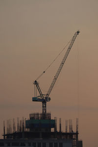 Cranes at commercial dock against sky during sunrise