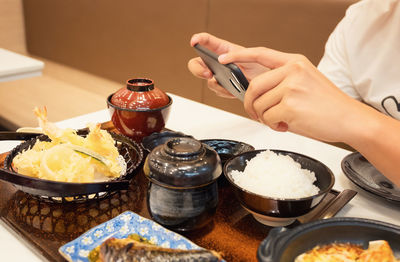 Cropped image of person photographing food on table