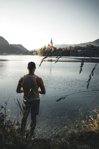 Rear view of man standing by lake