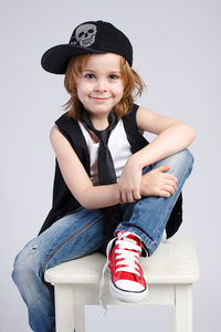 Portrait of a smiling girl sitting against wall