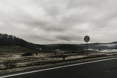 Road sign against cloudy sky