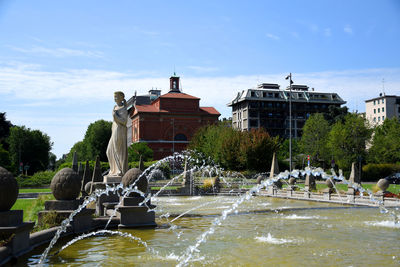 Fountain in pond against building