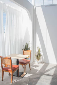 Empty chairs and table against wall in building