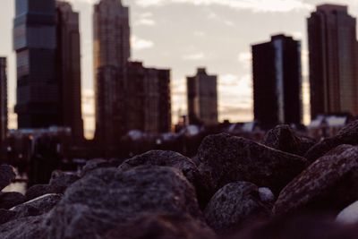 Rocks against buildings in city at sunset