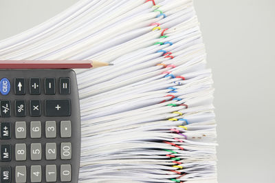 Close-up of calculator and pencil with stacked files against gray background