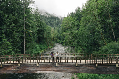 A young couple enjoys a hike on a bridge in the pacific northwest.