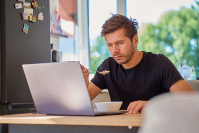 Young man using laptop while sitting at home