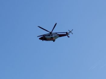 Low angle view of a helicopter against clear blue sky