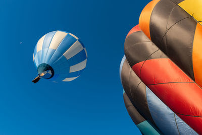 Low angle view of colorful hot air balloons flying against clear blue sky