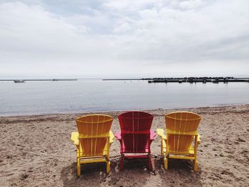 Deck chairs on beach against sky, toronto