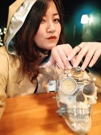 Portrait of young woman holding eyeglasses on table